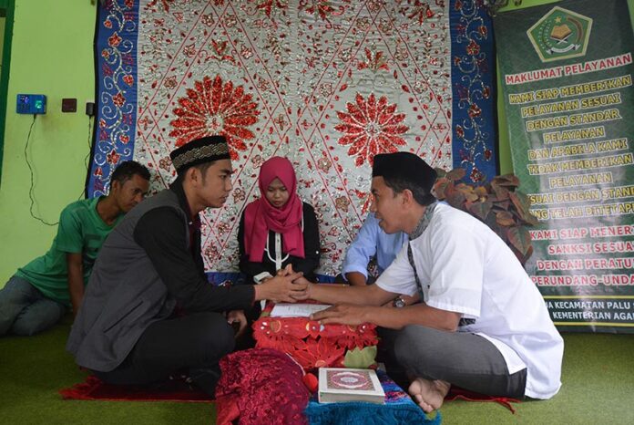 Petugas memandu akad nikah sepasang mempelai di Kantor Urusan Agama (KUA) Kecamatan Palu Selatan, Palu, Sulawesi Tengah, Kamis (22/12).