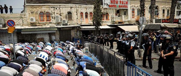 Palestinians pray on a street near a road block outside Jerusalem's Old city