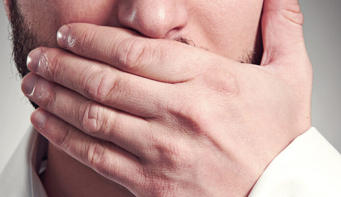 man holding hand over his mouth