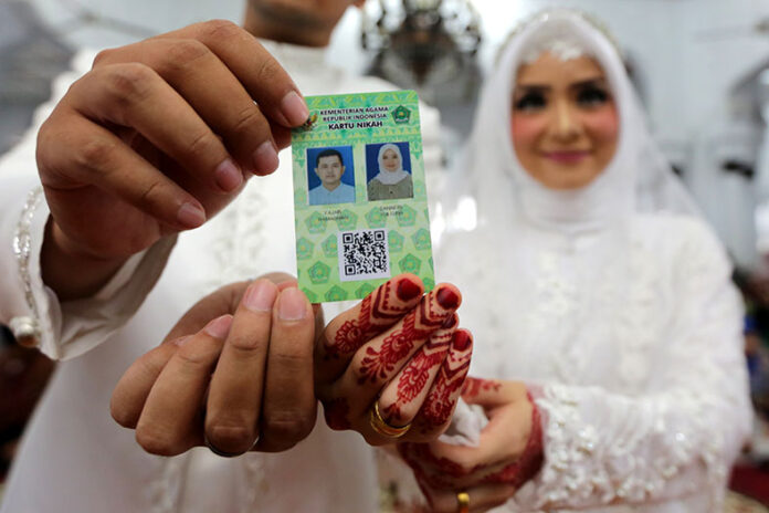 Pasangan pengantin memperlihatkan kartu nikah usai melaksanakan ijab kabul di Masjid Raya Baiturrahman, Banda Aceh, Aceh, Jumat (1/2/2019).